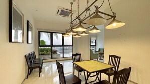 A dining area with a large table and chairs, a ceiling fan, and large windows offering a view of the outdoors. - Country Garden Danga Bay (Johor Bahru)
