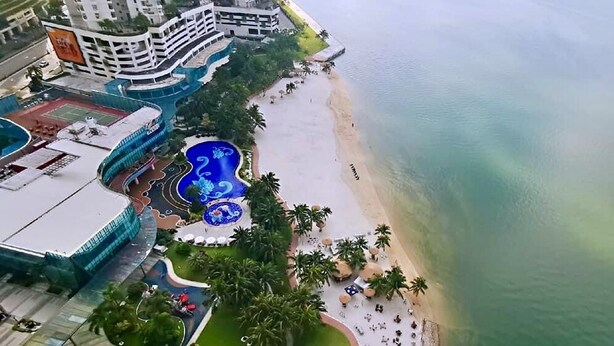 An aerial view of a coastal hotel with a beach, a swimming pool, and a tennis court. - Country Garden Danga Bay (Johor Bahru)