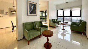 A modern lounge area with green sofas, a wooden table, and large windows offering a view. - Country Garden Danga Bay (Johor Bahru)