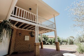 A two-story building with a balcony, brick walls, and a clear sky.