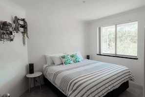 A bedroom with a bed, a window, and a small table. - Seascape - Where Coastal Fun and Adventure Meet (Eagle Bay)