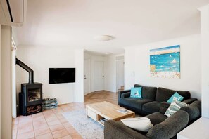 A living room with a sofa, a coffee table, a fireplace, and a painting on the wall. - Seascape - Where Coastal Fun and Adventure Meet (Eagle Bay)