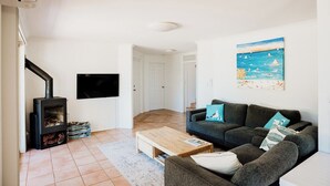 Een woonkamer met een open haard, een bank, een salontafel en een schilderij aan de muur.