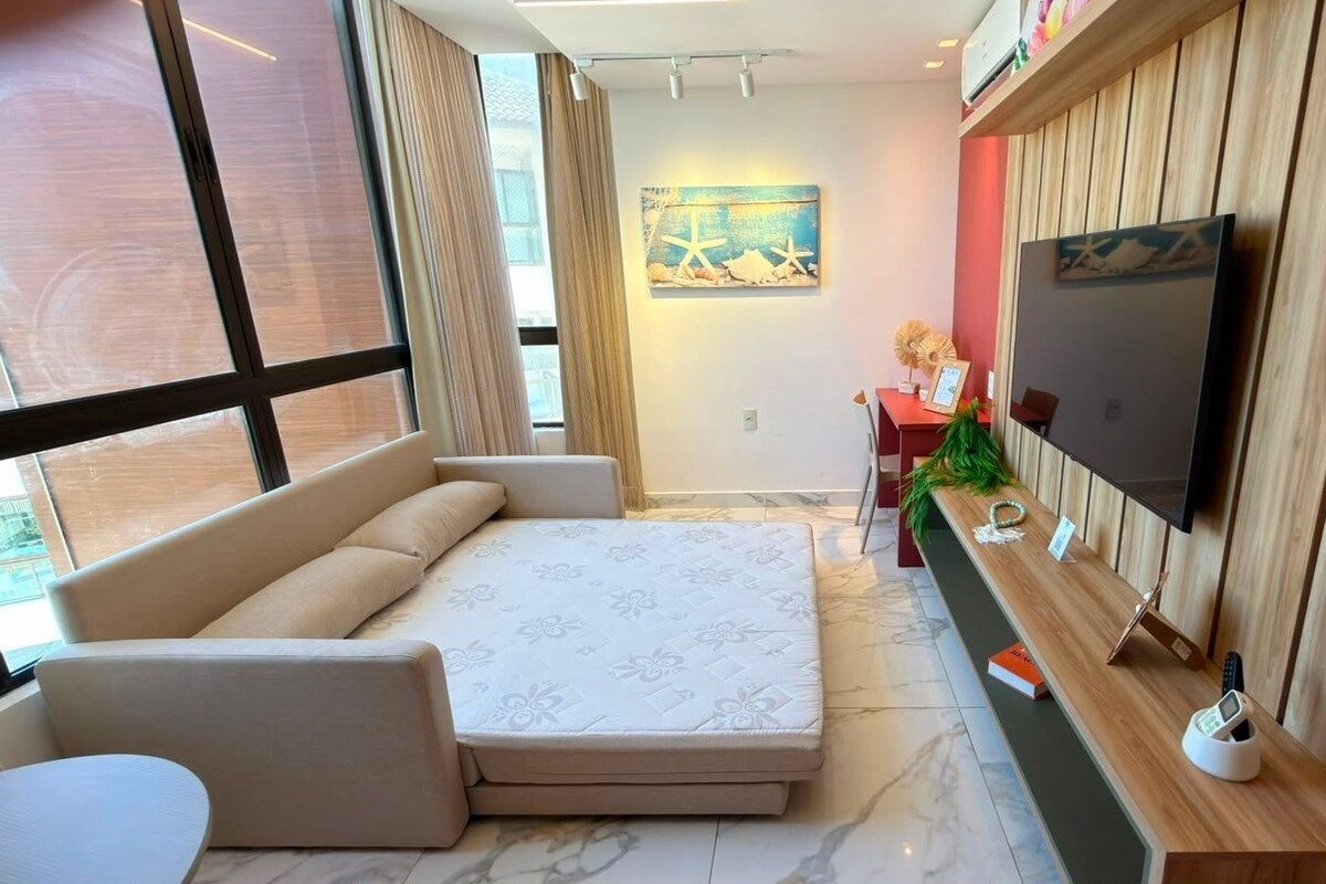 Una sala de estar moderna con un sofá, un televisor de pantalla plana y un mueble bajo para la televisión.