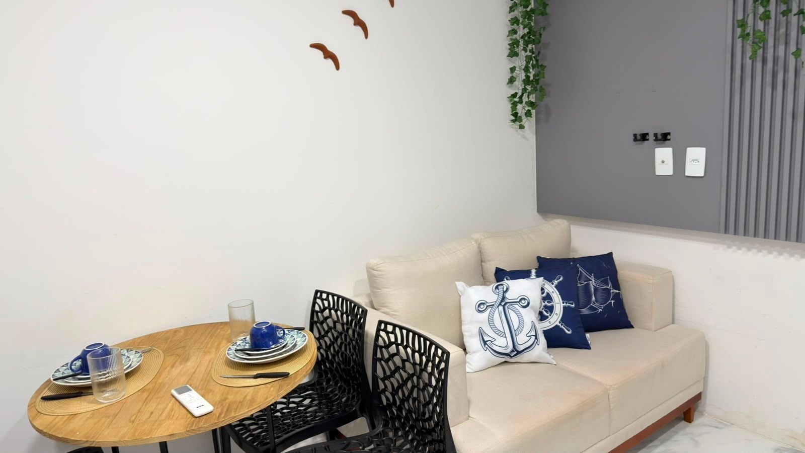 A modern living room with a beige sofa, a wooden dining table with chairs, and decorative pillows.
