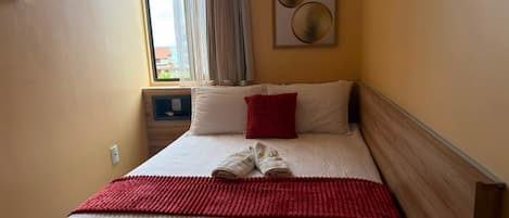 Una habitación de hotel con una cama, una toalla roja y vistas al exterior a través de una ventana.