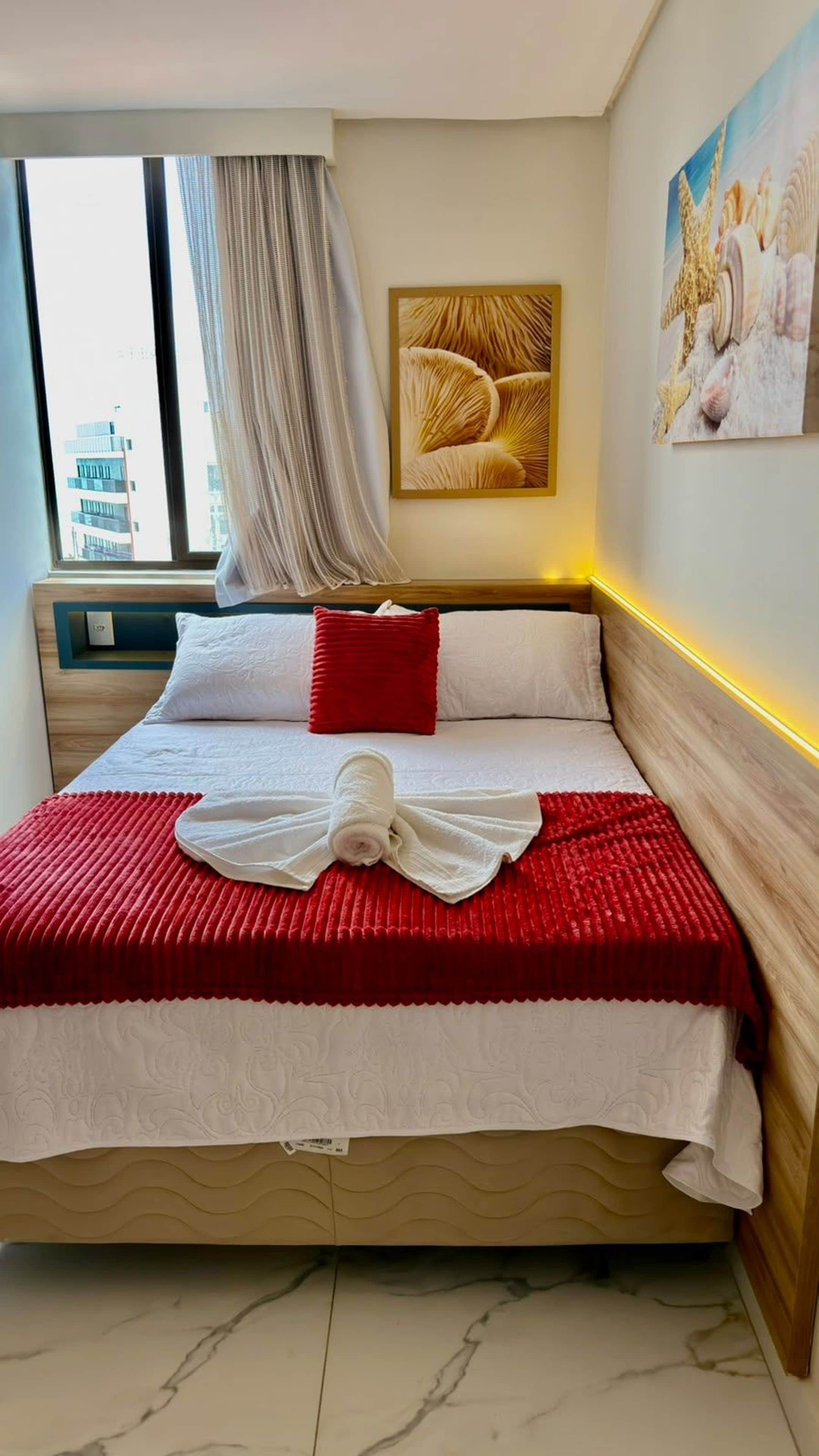 Quarto de hotel com cama, janela com cortinas, obra de arte na parede e vista para a cidade.