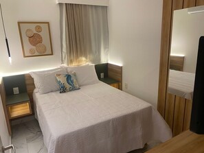 A neatly arranged bedroom with a large bed, two bedside tables, a wall-mounted artwork, and a mirror. - Porto Atlantis (Ipojuca)