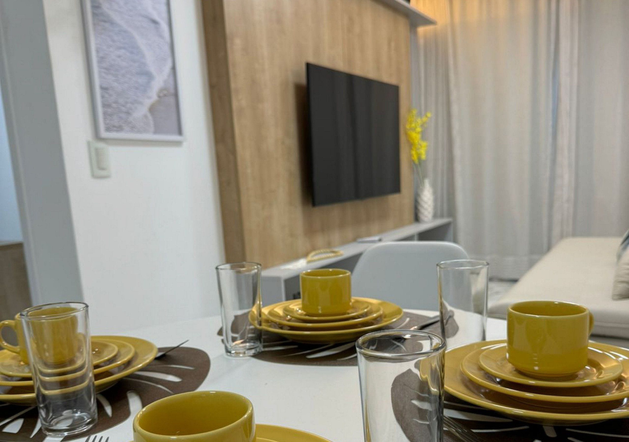 A dining table set with yellow and brown plates, glasses, and cutlery.