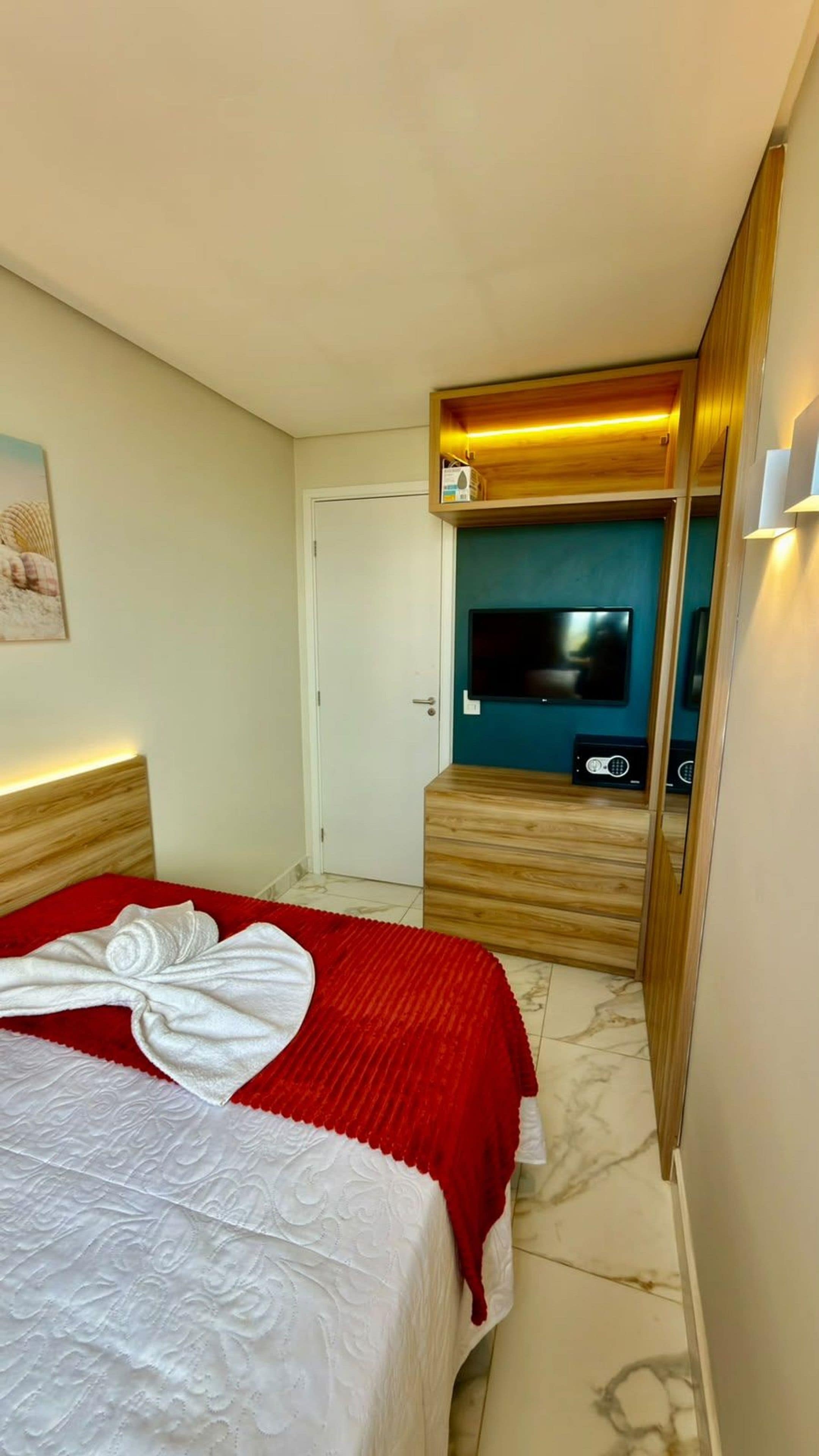 A hotel room with a bed, a television, and a wooden cabinet.