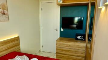 A hotel room with a bed, a television, and a wooden cabinet.