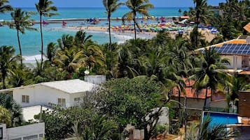 Na praia, areia branca, barracas de praia de cortesia, espreguiçadeiras