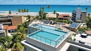 Una piscina al aire libre, sombrillas, sillones reclinables de piscina