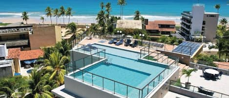 Una piscina al aire libre, sombrillas, sillones reclinables de piscina