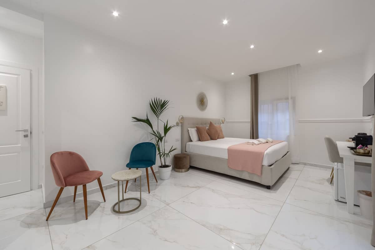 A modern bedroom with a bed, a desk, a chair, and a potted plant.