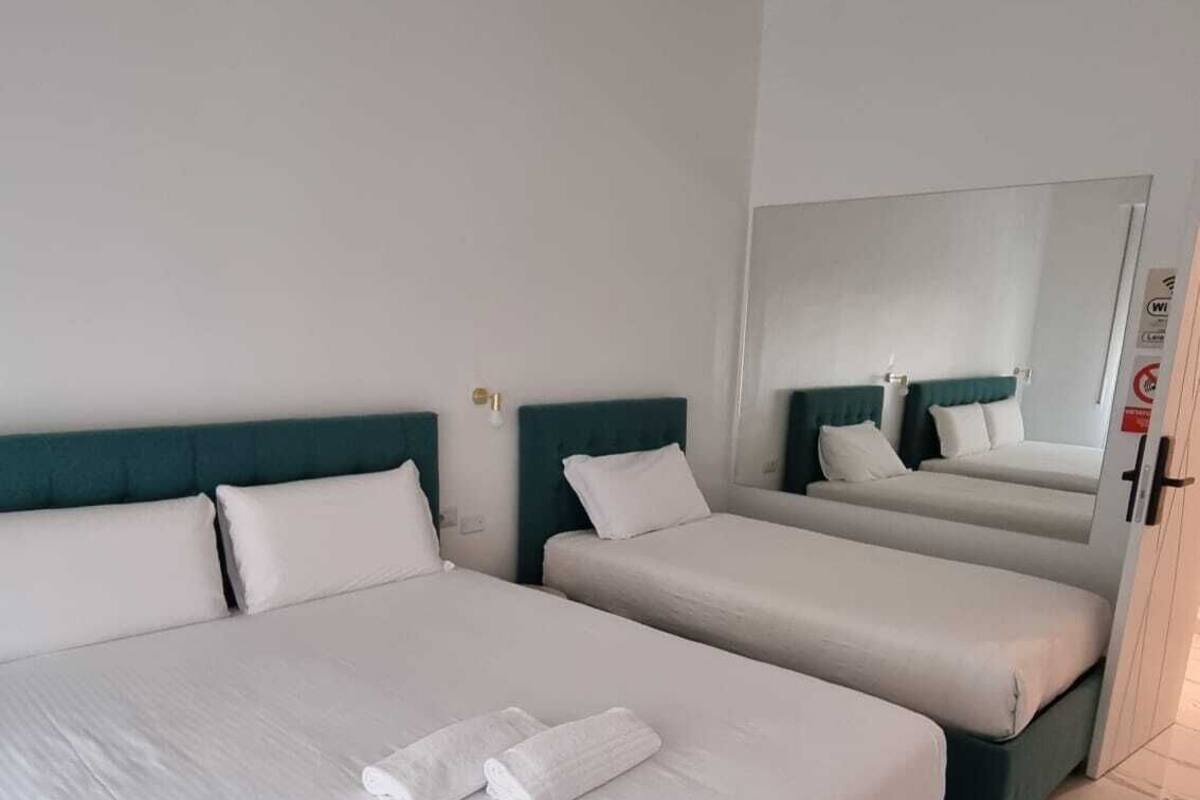 A hotel room with a large bed, a smaller bed, and a mirror on the wall.