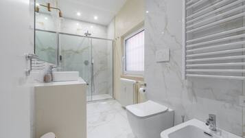 Ein modernes Badezimmer mit Duschkabine, Toilette, Bidet und Waschbecken.