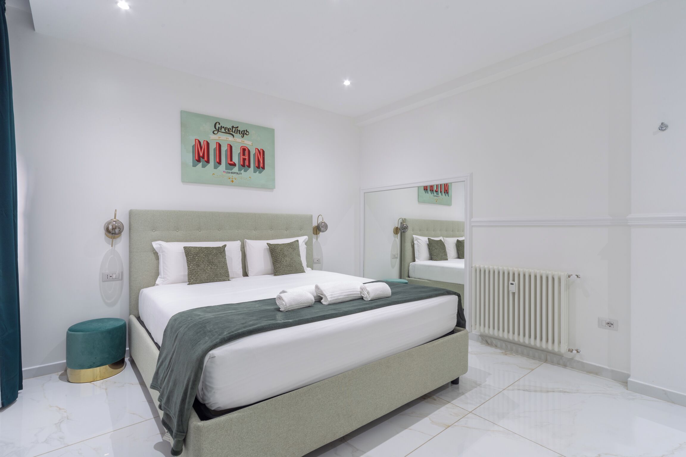 A modern bedroom with a large bed, a bedside table, a mirror, and a radiator.