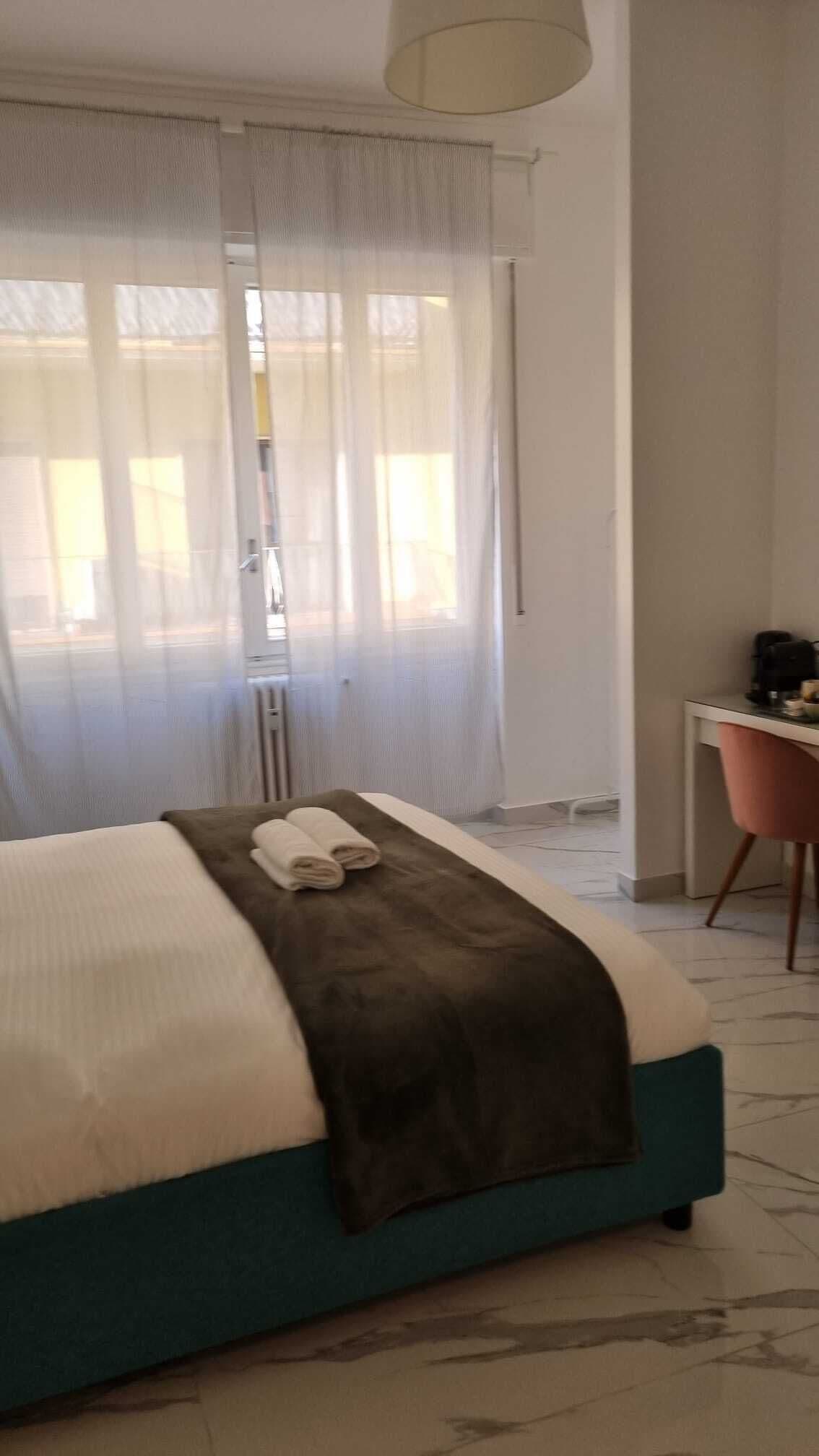 A hotel room with a bed, a desk, and a chair.