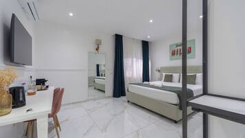 Een moderne hotelkamer met een bed, een bureau met stoel, een flatscreen televisie en een spiegel.