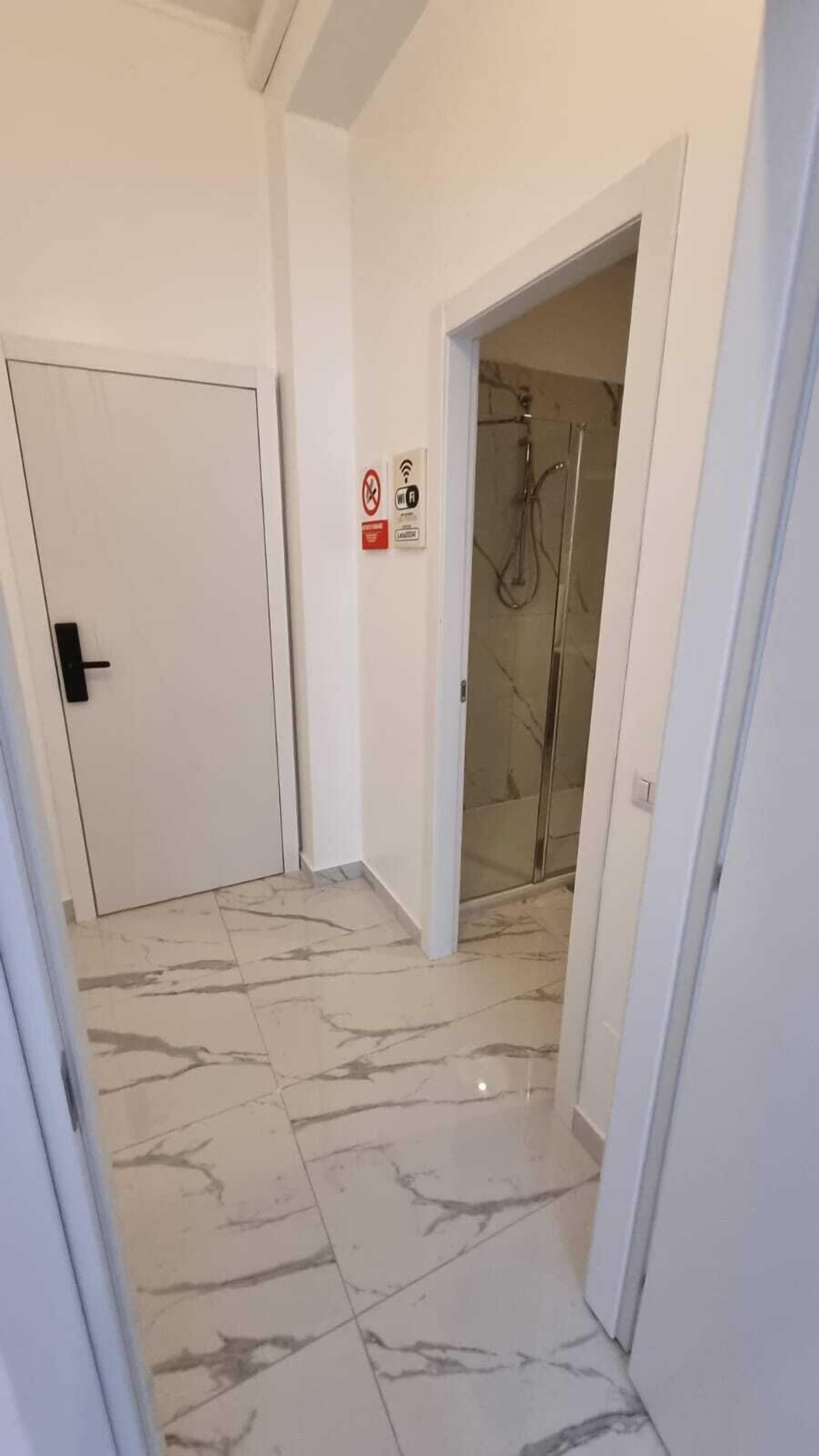 A hallway with a tiled floor, a closed door, and a shower area visible through a glass door.