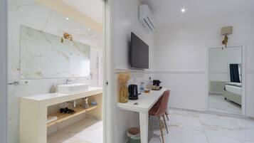 Une salle de bain moderne avec un meuble-lavabo en marbre, un grand miroir et un téléviseur fixé au mur.