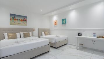A hotel room with two beds, a minibar, and a cityscape painting on the wall.