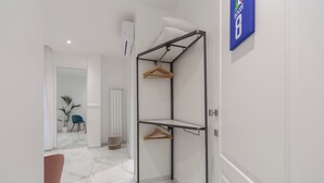 A modern, minimalist room with a built-in closet featuring wooden hangers and a white pillow. - Leia Hospitality (Milan)