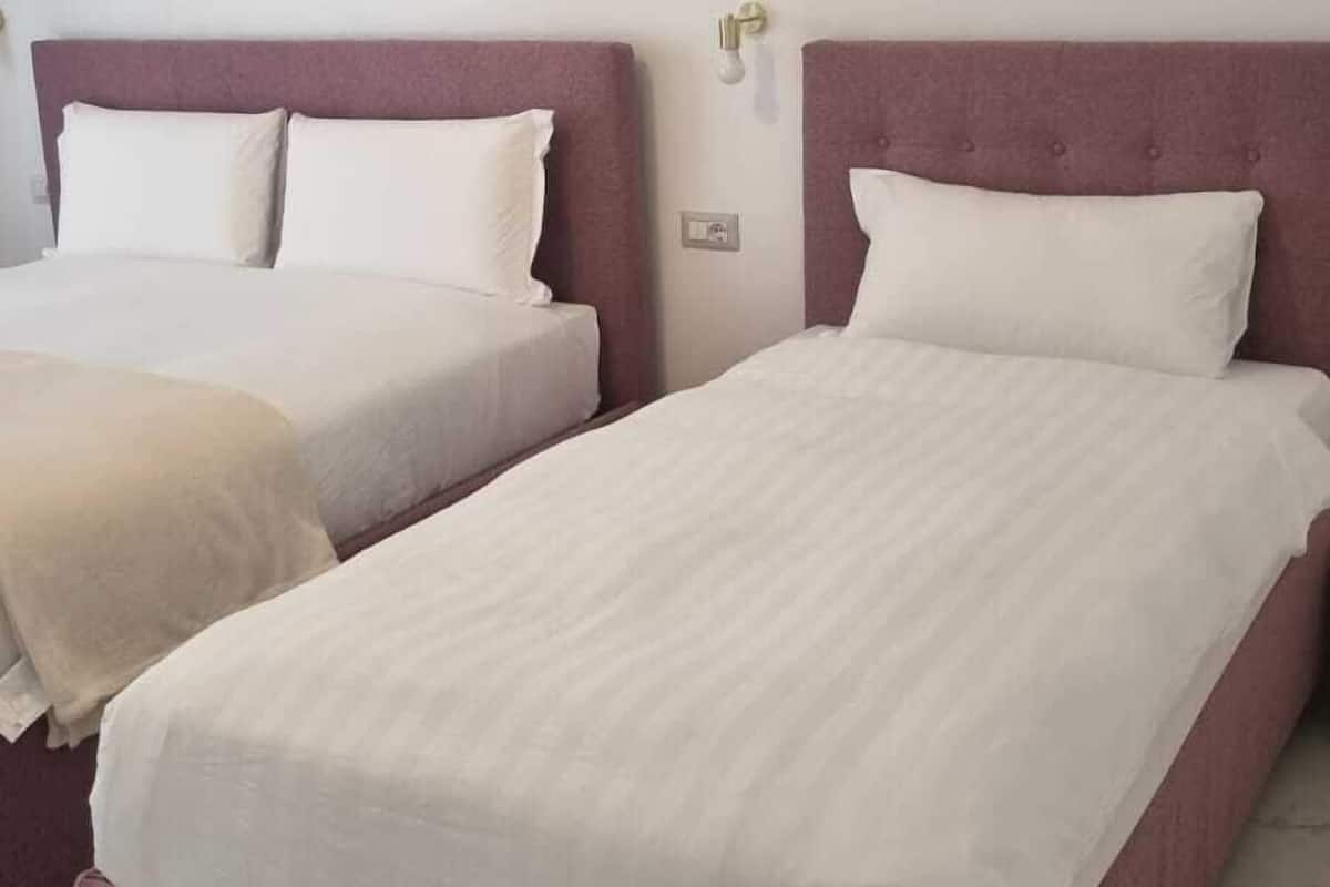 Two single beds with headboards, white bedding, and a marble floor.