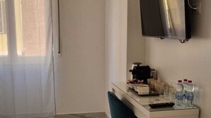 A hotel room with a marble floor, a desk with a chair, a television mounted on the wall, and a window with curtains. - Leia Hospitality (Milan)