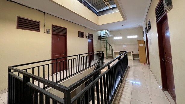 Un intérieur à plusieurs niveaux, avec un escalier, des rampes en métal et des portes.