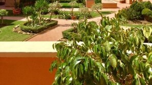 Un hôtel moderne à plusieurs étages, doté d’une cour aménagée avec des palmiers et surplombant un ciel d’un bleu éclatant.