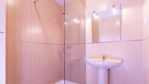 A bathroom with a glass shower enclosure, a white sink, and a mirror above the sink.