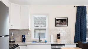 A modern kitchen with white cabinets, a built-in oven, a coffee maker, and a dishwasher. - Dog-friendly Single-Family Home w Free Parking, Washer, Dryer in NYC "Nantucket" (The Bronx)
