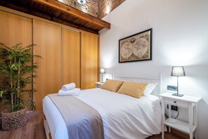 Een hotelkamer met een bed, nachtkastjes, een lamp, een kaart aan de muur en een bloempot.