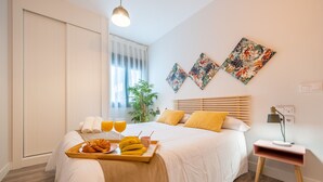Une chambre d’hôtel avec un lit, une table de chevet, un plateau avec le petit-déjeuner et une fenêtre avec des rideaux.