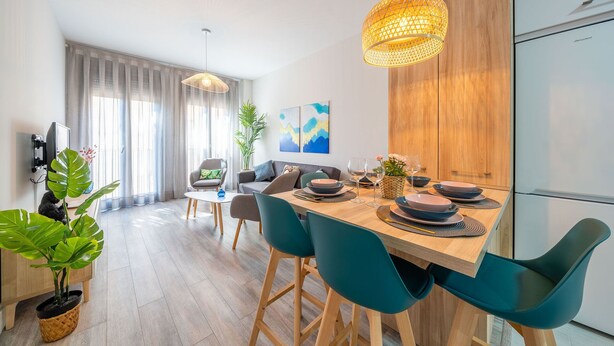 Un espace repas moderne avec une table en bois, des chaises de couleur turquoise et un luminaire suspendu.