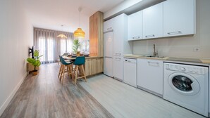 Une cuisine moderne avec des meubles blancs, un lave-vaisselle intégré et un lave-linge.