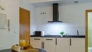 Eine moderne Küche mit Mikrowelle, Toaster und Spüle. Auf dem Tisch steht eine Schale mit Früchten und ein Glas Orangensaft.