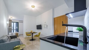 Eine moderne Küche mit einem schwarzen Spülbecken, einem Essbereich mit gelben Stühlen und einem grauen Sofa.