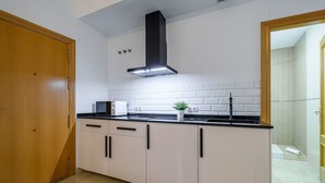 Eine moderne Küche mit weißen Schränken, schwarzen Arbeitsplatten und einer schwarzen Dunstabzugshaube. Ein kleiner Blumentopf steht ebenfalls bereit.