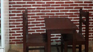 A wooden table and chairs against a brick wall. - Hotel O Rasya Homestay Near SD Negeri 6 Mataram (Mataram)