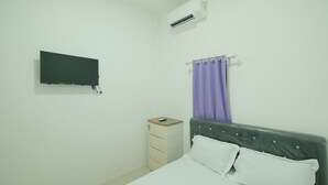 A bedroom with a bed, a dresser, a TV mounted on the wall, and a purple curtain. - Hotel O Rasya Homestay Near SD Negeri 6 Mataram (Mataram)
