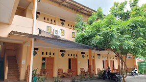 A two-story building with a covered porch, wooden doors, and a staircase leading to the upper floor. - Hotel O Rasya Homestay Near SD Negeri 6 Mataram (Mataram)