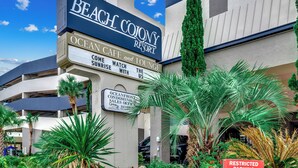 Ein Gebäude mit einem Schild für das Beach Colony Resort, inklusive Annehmlichkeiten wie Café, Lounge und Apartments direkt am Meer.