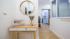 Un couloir avec un bureau en bois, un miroir rond et une plante en pot.