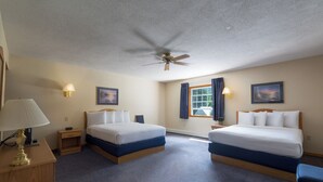 A hotel room with two beds, a ceiling fan, a window with curtains, and a desk with a lamp. - Adirondack Retreat Inn & Suites - Superior Rental House (Lake George)