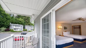 A hotel room with two beds, a balcony, and a view of neighboring houses. - Adirondack Retreat Inn & Suites - Superior Rental House (Lake George)