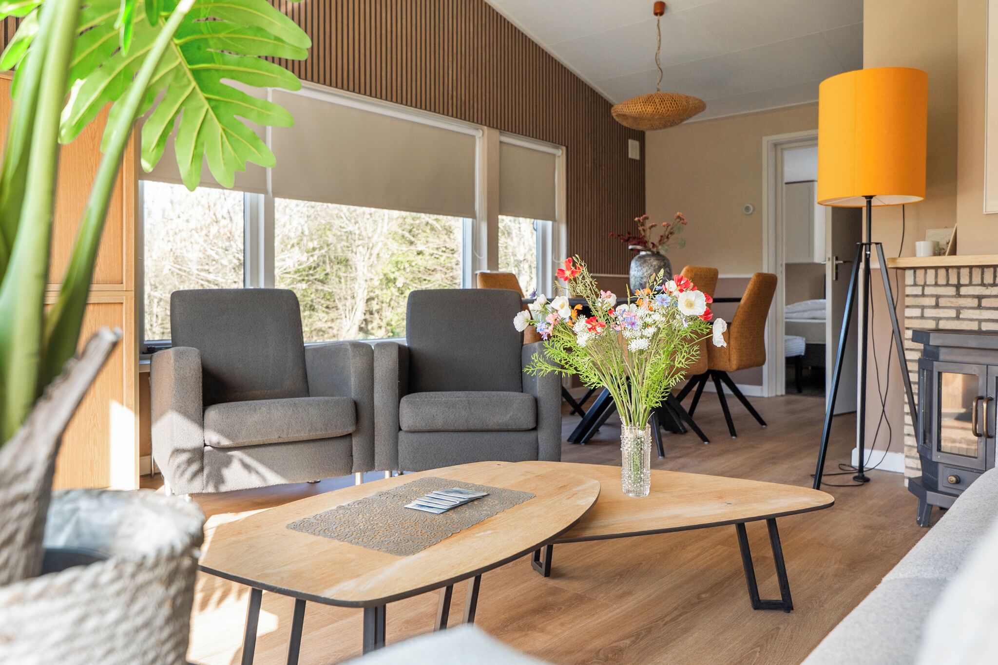 A modern living room with a sofa, chairs, a coffee table, and a vase of flowers.