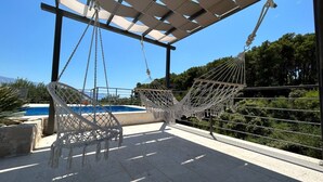 A hammock under a pergola by a pool with a clear view of the surrounding greenery and mountains. - Villa Blue Bay with private pool (Selca)